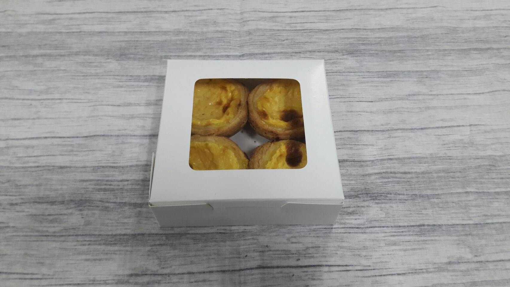 กล่องทาร์ต 4 ชิ้น (ขนาดถ้วยทาร์ต 6 ซม.) กล่องทรงแบน (หน้าต่างพลาสติก) ขนาด12.5x12.5x4.0ซม. สีขาว ราคา 100 บาทต่อแพ็ค (20 ใบ)